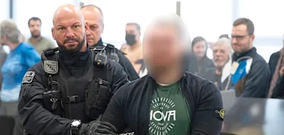 Unter Applaus wird der mutmaßliche Chef der „Hammerbande“ zur Anklagebank geführt